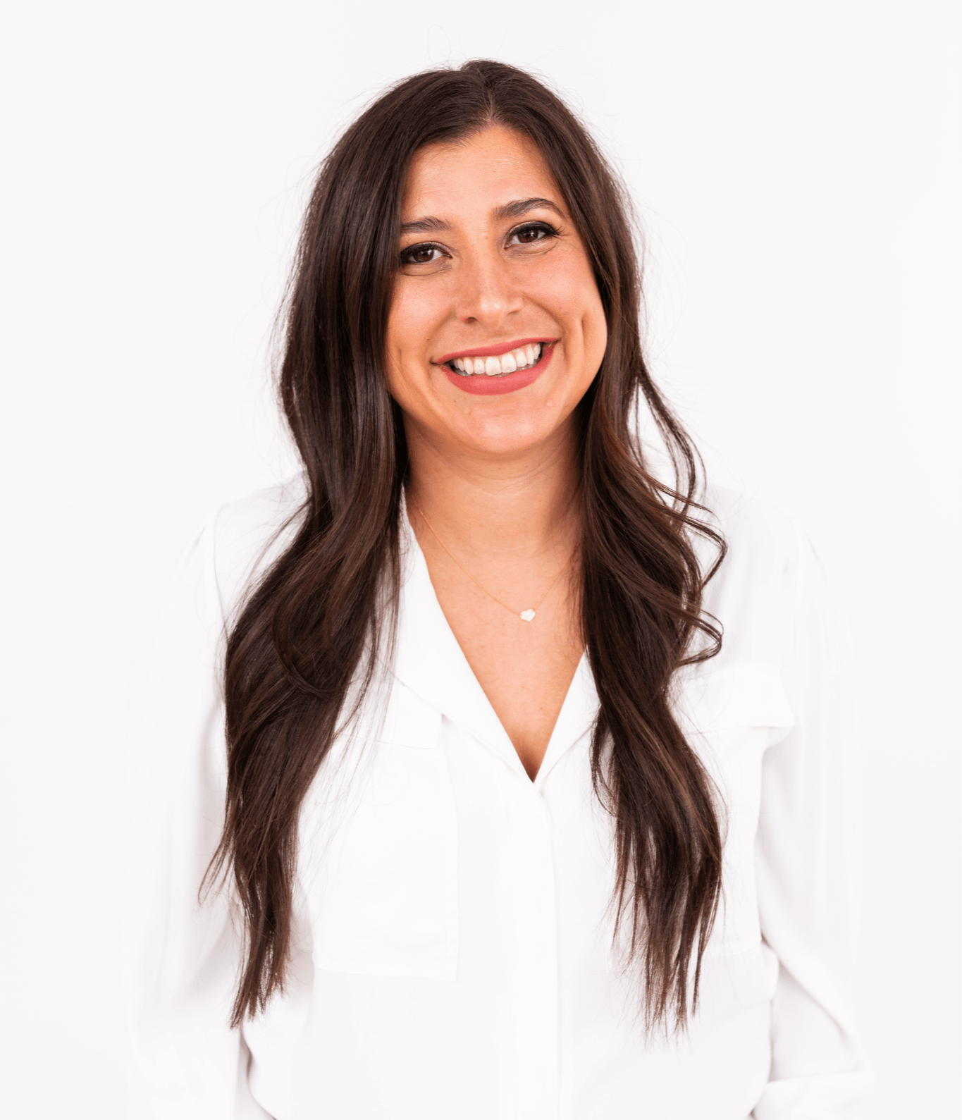 Young woman with long dark hair smiling, wearing a white blazer against a plain white background.