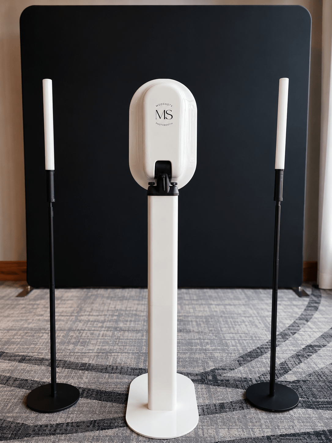 Hand sanitizer dispenser with two tall, thin speakers on black stands in front of a black background.