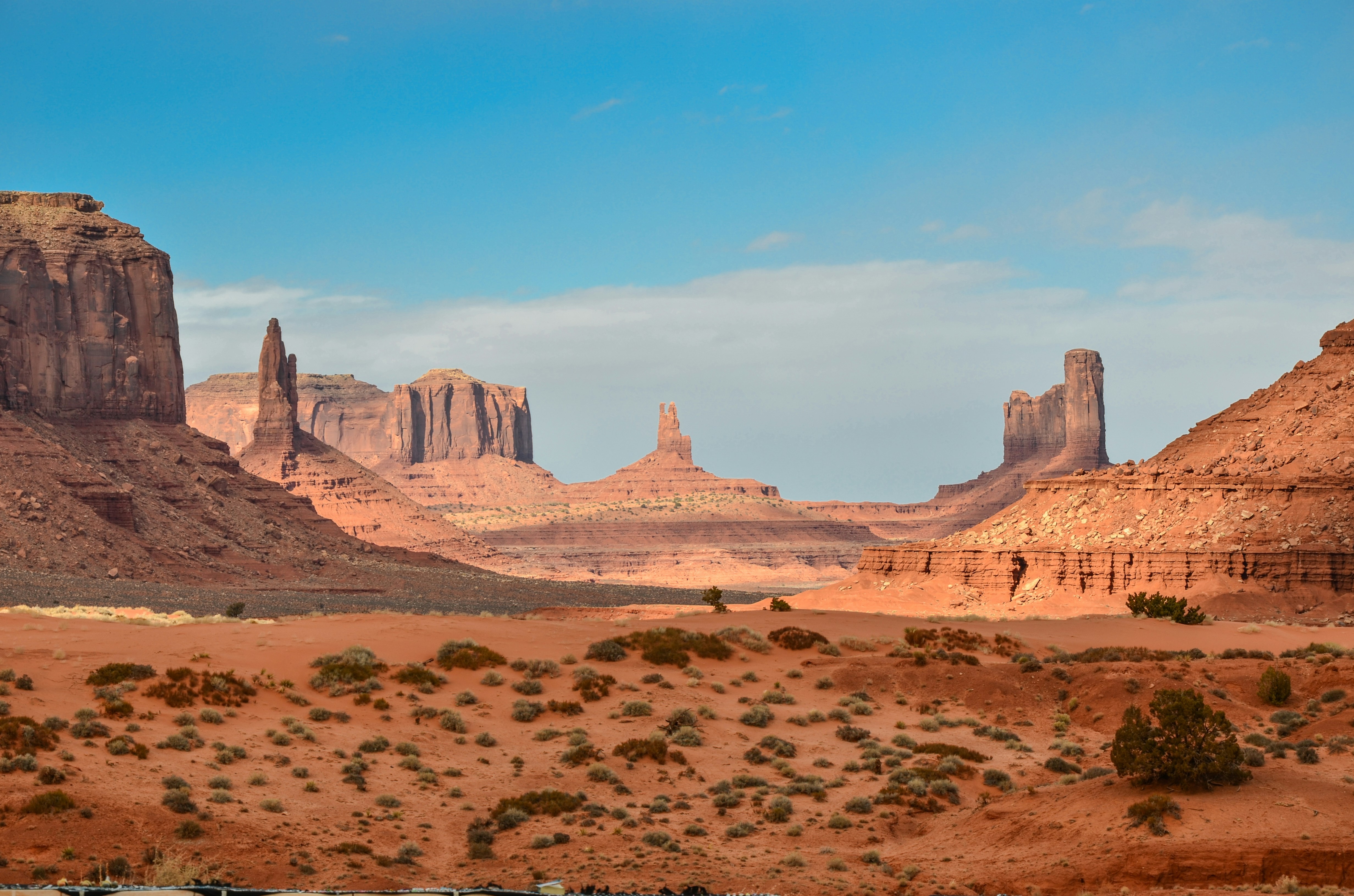 Desert landscape with rock formations and mesas under a blue sky with clouds.