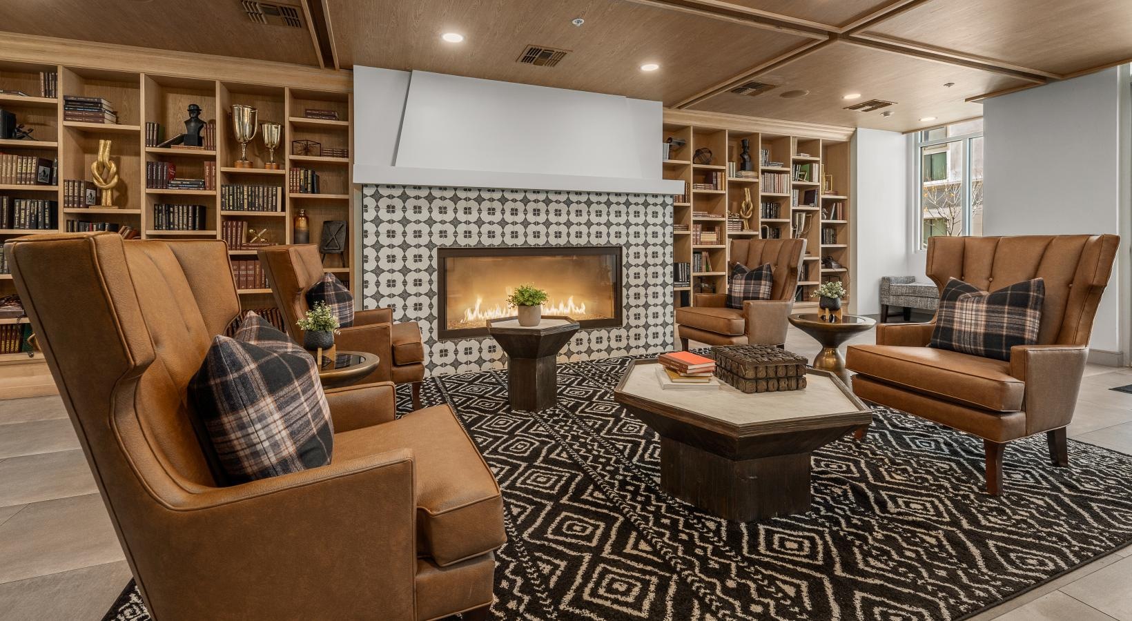 Living room with armchairs, a fireplace, bookshelves, and a patterned rug.
