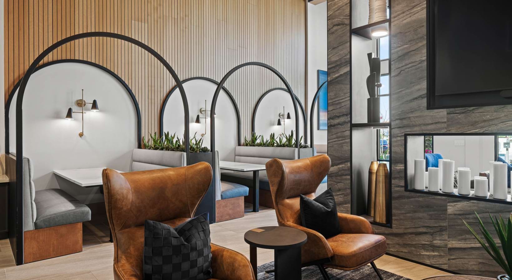 Modern interior with booths, leather chairs, and decorative arches, featuring wood and stone textures.